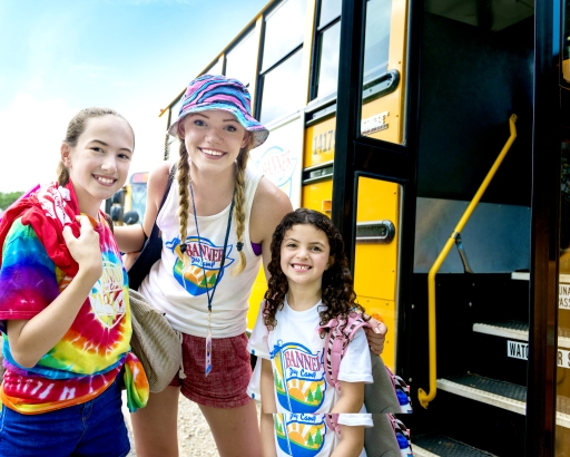 Two campers getting off the bus smiling with a CIT camper