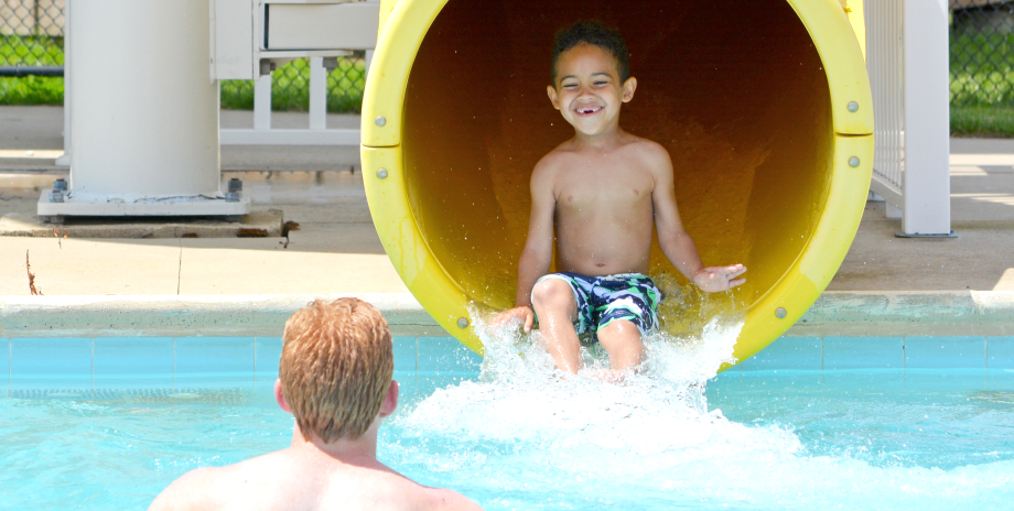 Boy camper sliding down a water slide