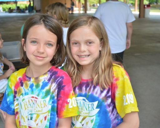 Two campers smiling together in banner day camp shirts