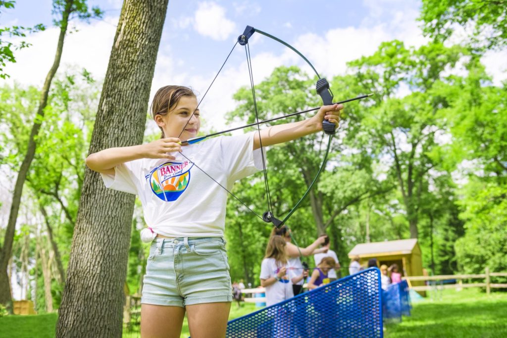 A camper aims and prepares to shoot an arrow