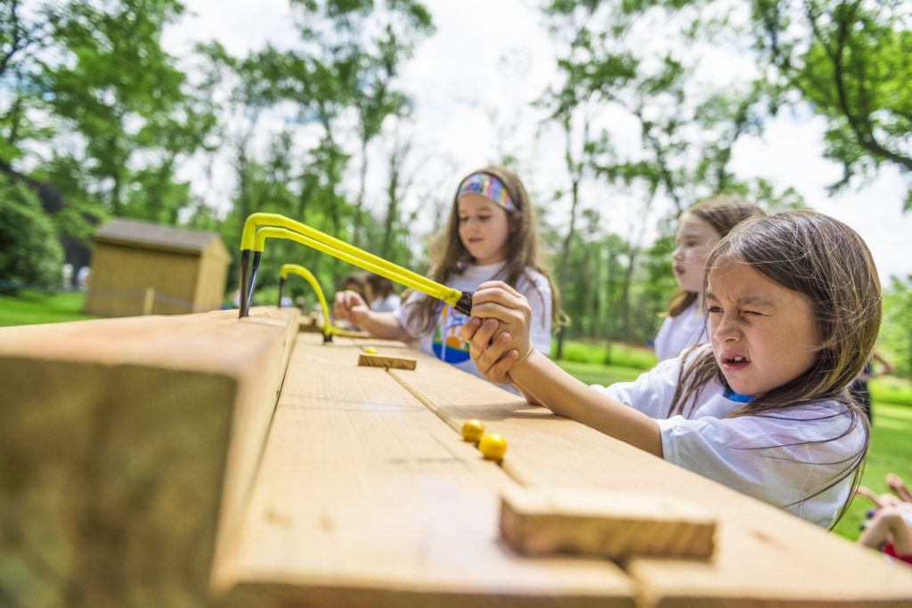 A camper focusing on her target at the slingshot range