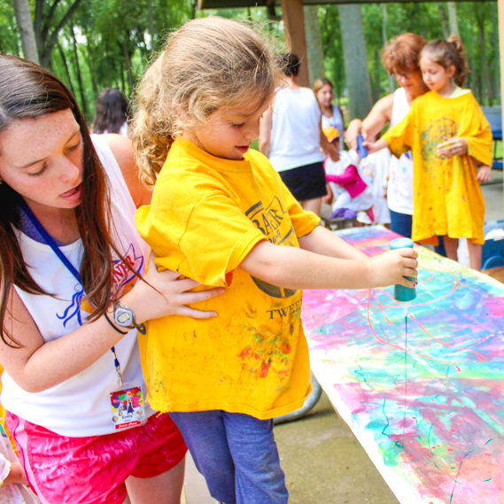 Girl camper doing arts and crafts with the help of a staff member