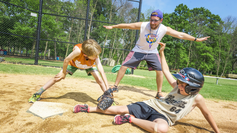 Male staff member calling "safe" at a baseball game at home plate