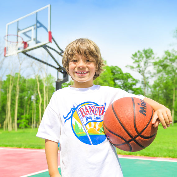 Boy camper holding a basketball and smiling