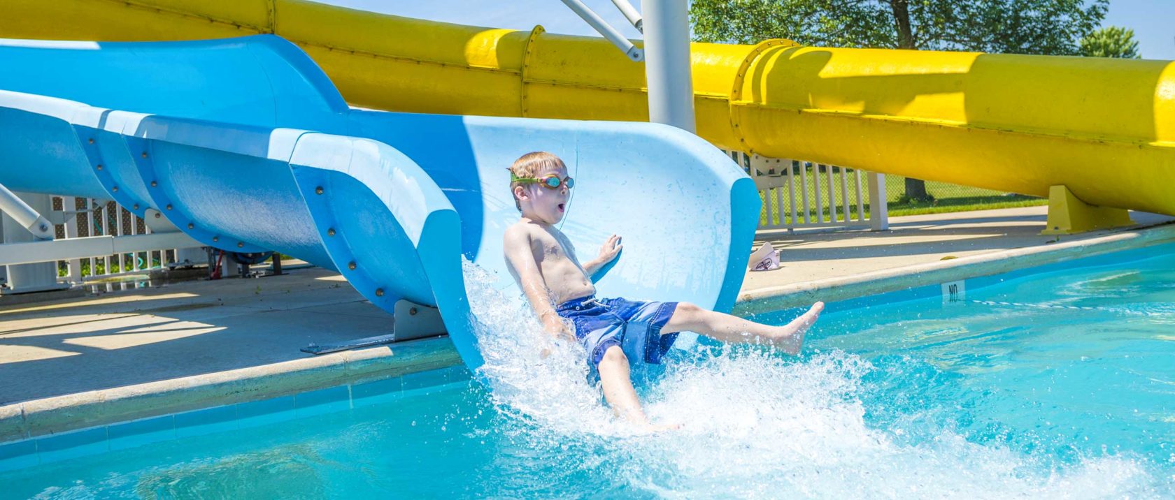 Boy camper sliding down water slide