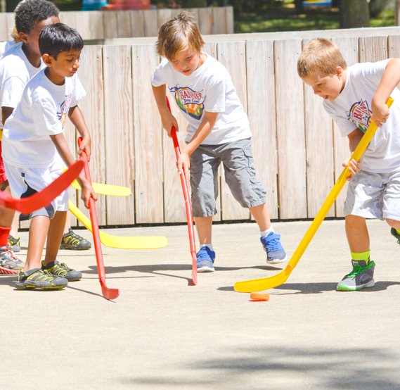 Boy campers playing street hockey