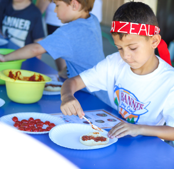 Boy camper making a mini pizza