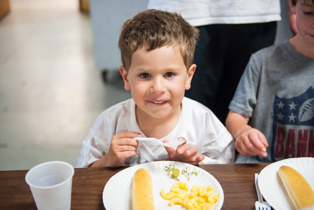 A young boy smiles with his plate at the table