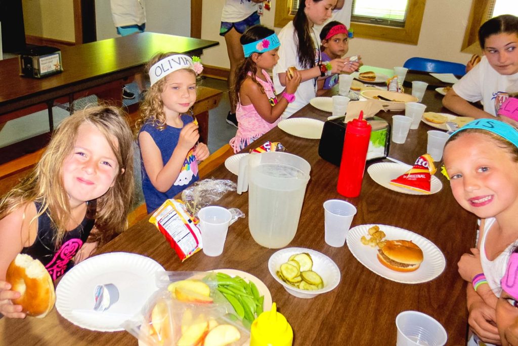 A group of young campers eating at a table