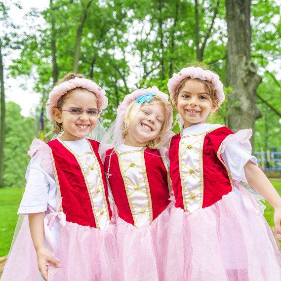 Three girl campers dressed up in princess costumes smiling