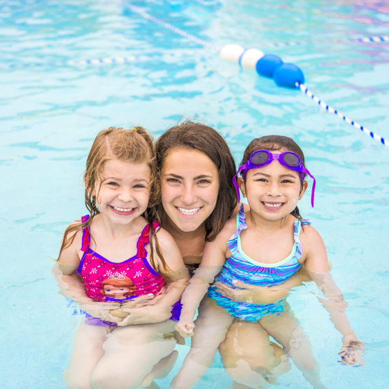 Two girl campers in the pool with a female staff member