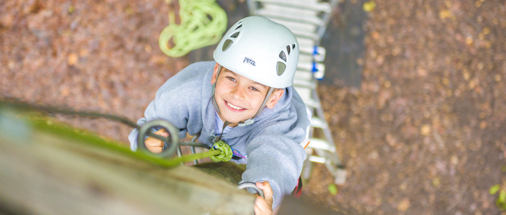 Boy camper climbing a pole on the ropes course