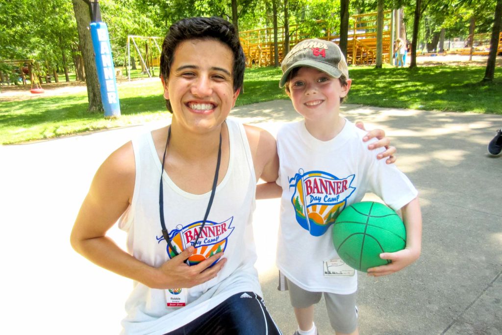 A camper and a counselor smiling with a basketball