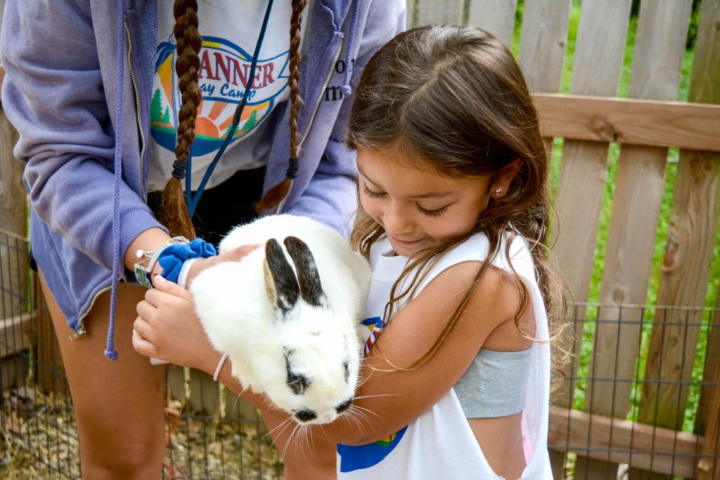 A young girl hugging a baby bunny