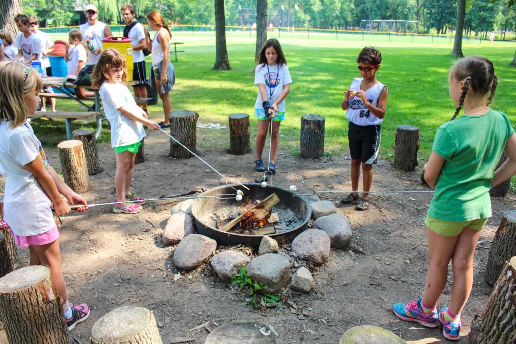 young children around a campfire roasting marshmallows