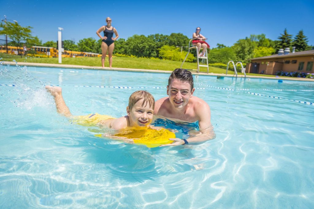 a counselor teaching a camper how to swim