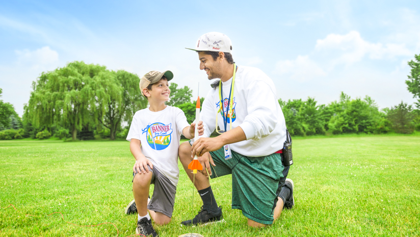 Male staff member helping a boy camper launch a rocket