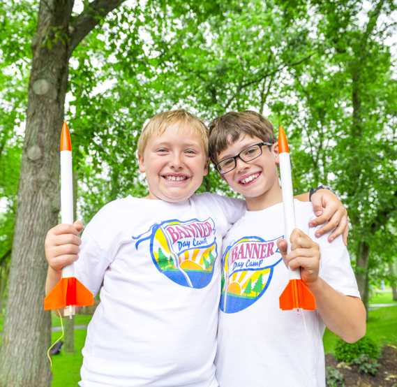 Two boy campers holding rockets and smiling