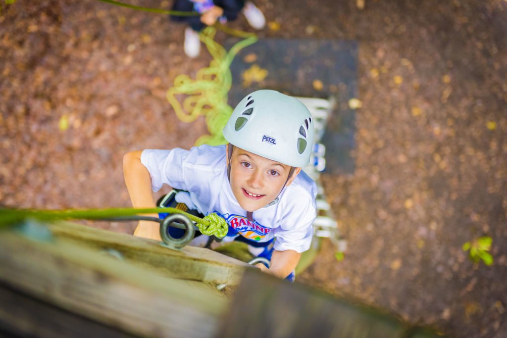 A boy looking up while climbing the rock wall