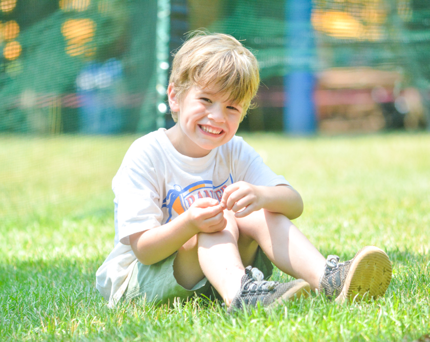 Boy camper smiling sitting in the grass