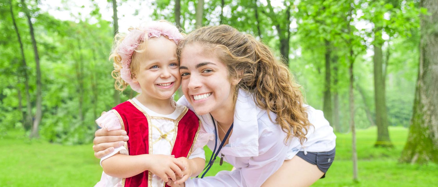 Female staff member smiling next to a young girl camper