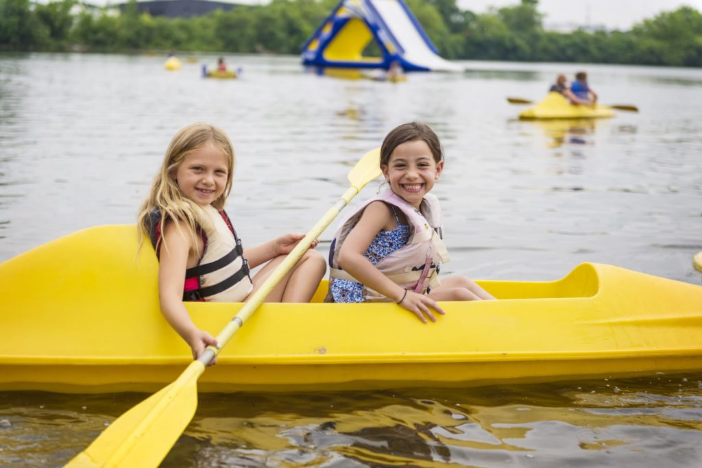 Two female campers in a yellow canoe on the lake