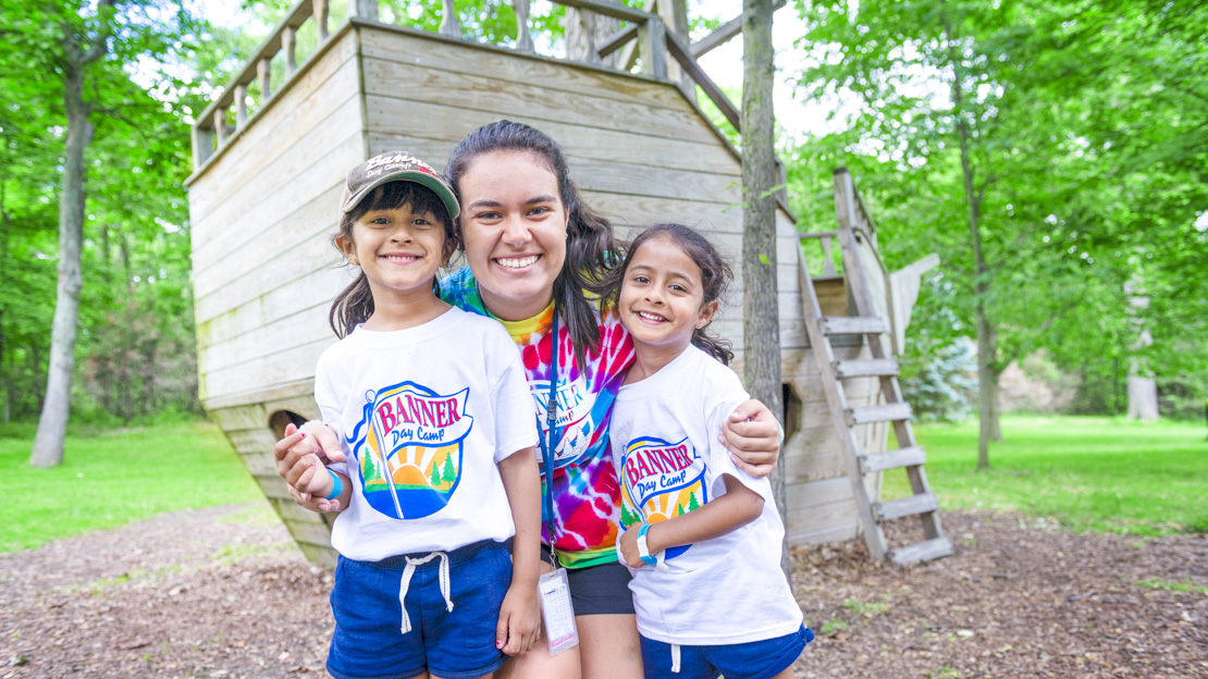 Female staff member smiling with two girl campers