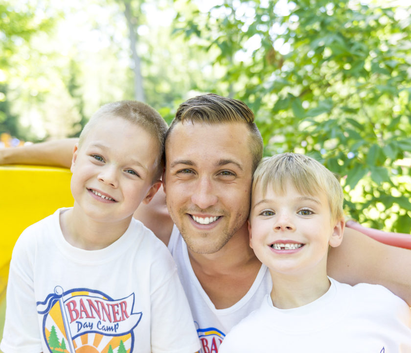 Two boy campers smiling with a male staff member