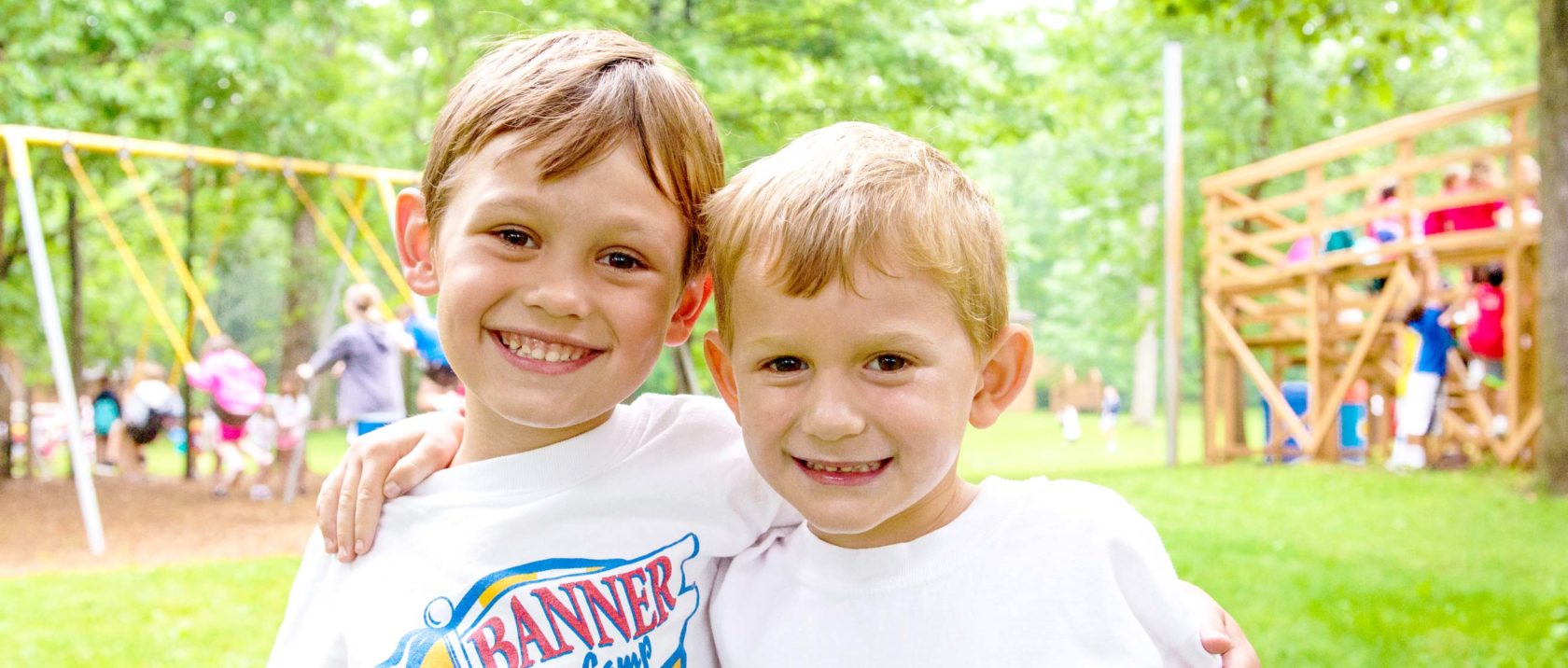 Two boy campers with arms around each other smiling