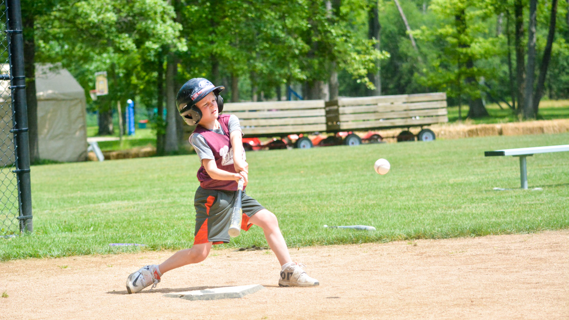 Camper swinging a bat at a baseball