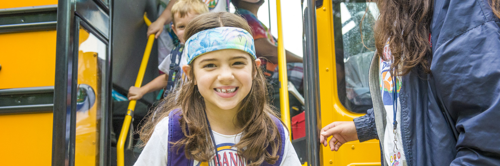 Camper smiling as she gets off the bus