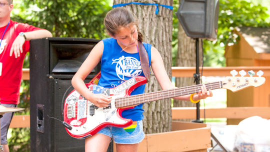 Girl camper playing the electric guitar on stage