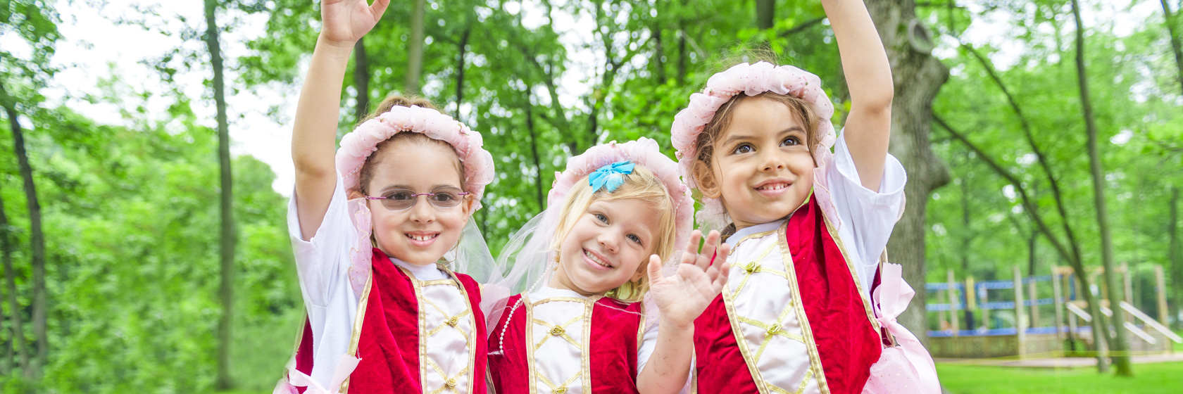 Three young girl campers all dressed up in the same princess dress smiling together