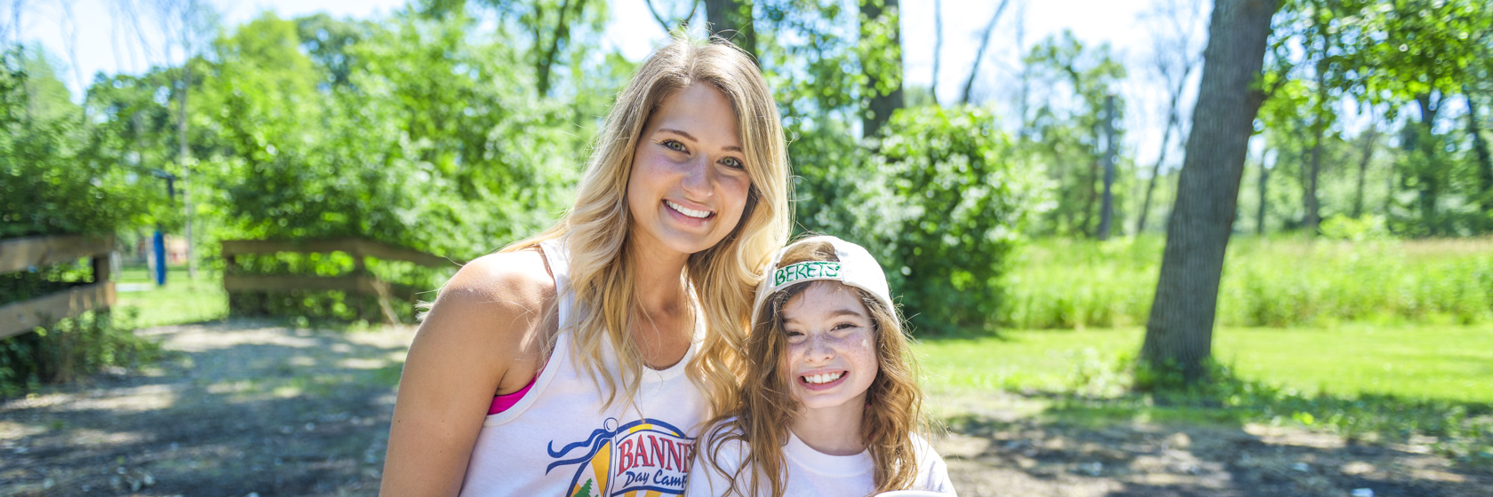 Staff member with a young camper during lunch