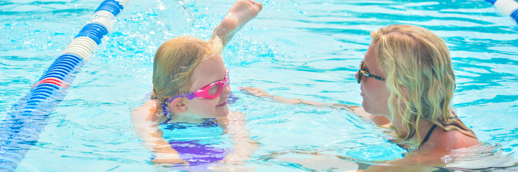 Staff member helping a camper learn how to swim