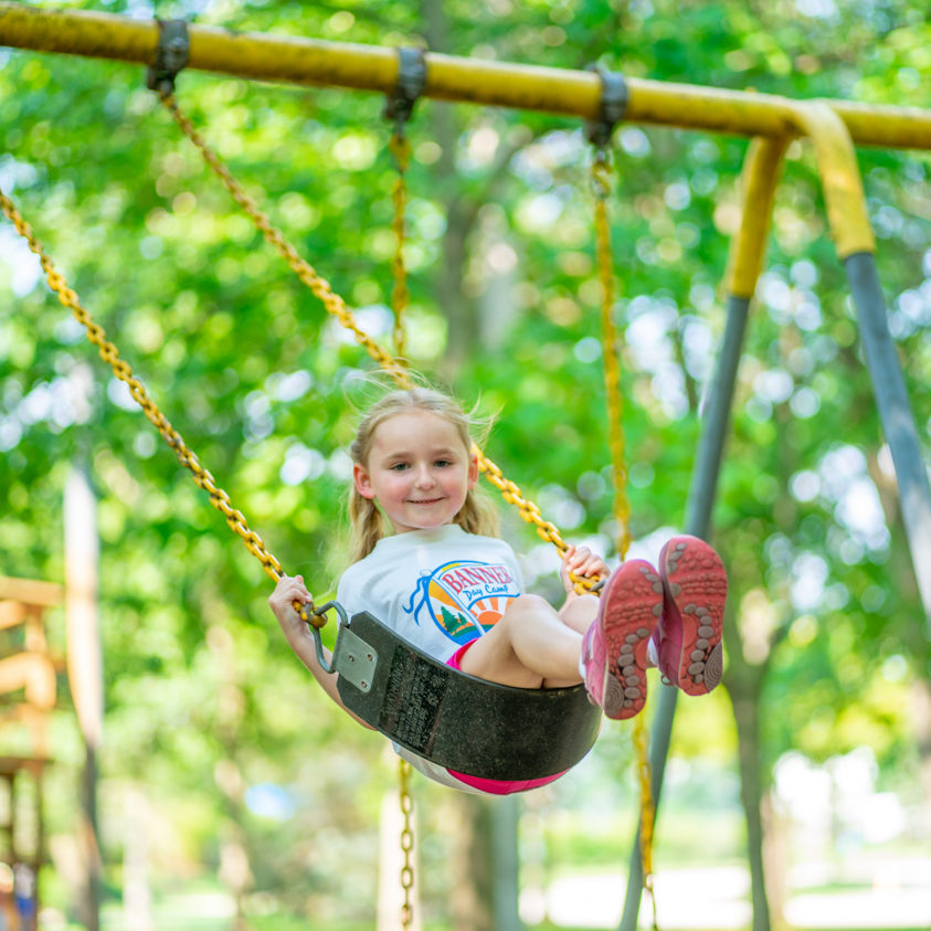 Girl camper swinging on a swing set