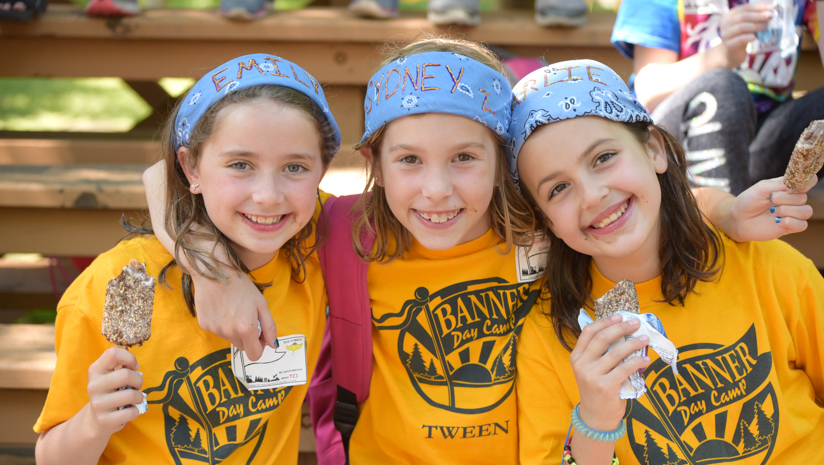 Three girl campers smiling together with ice cream