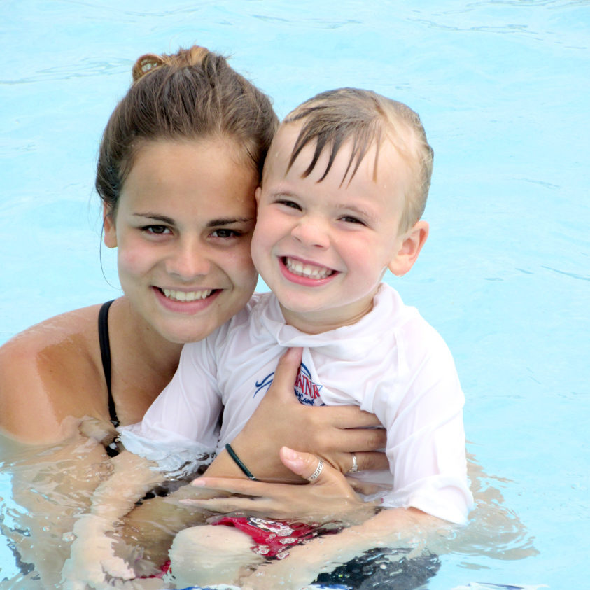 Female counselor with a boy camper in the pool smiling