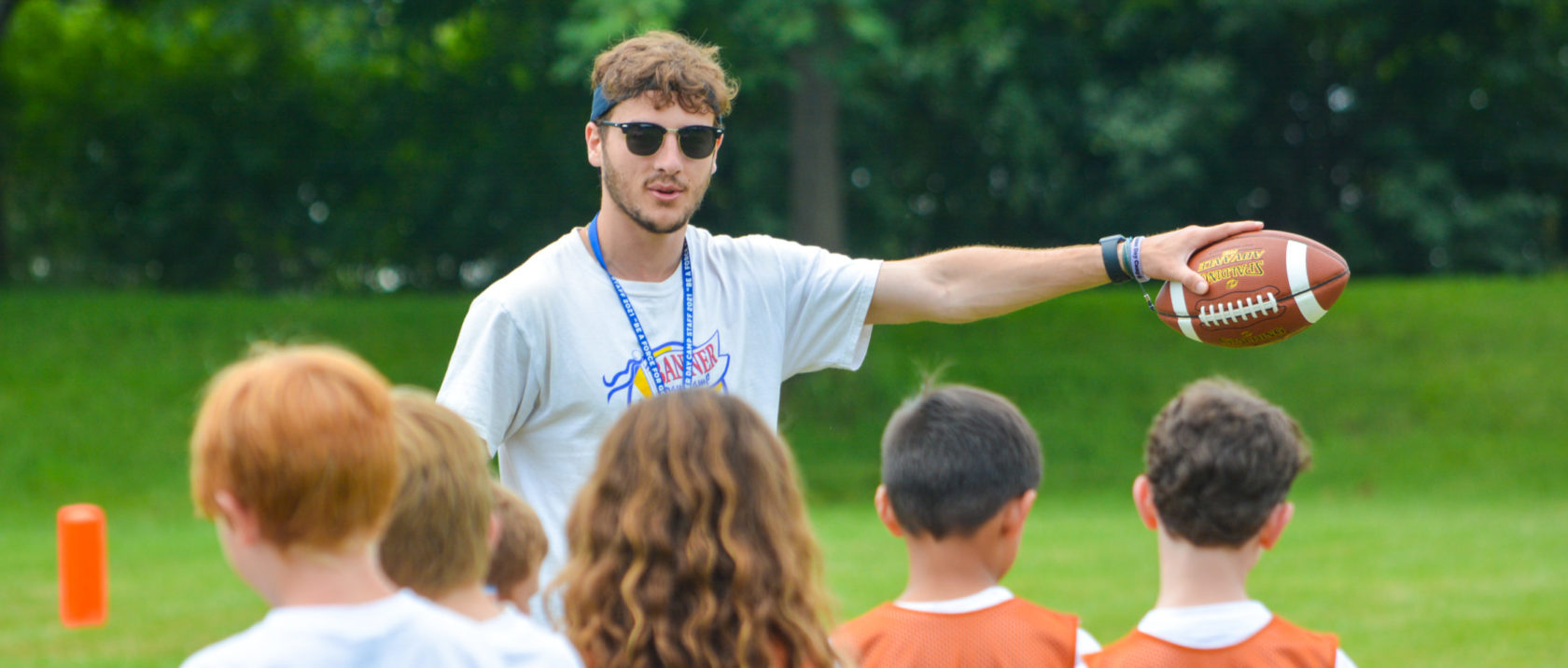 Male counselor coaches a group of campers at football