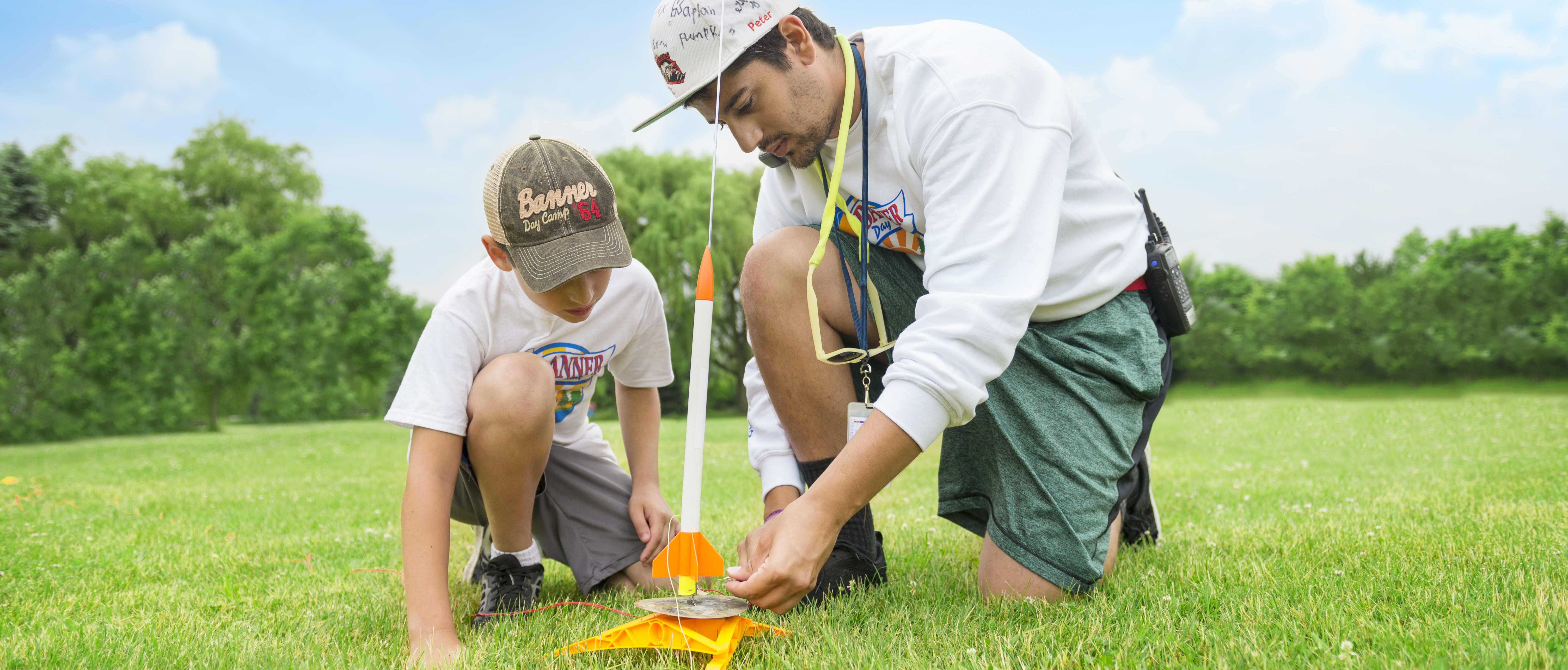 Male counselor helps male camper launch a rocket